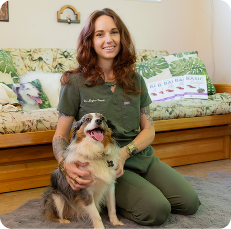 Woman in green scrubs sitting on floor with a happy Australian Shepherd dog in a cozy room